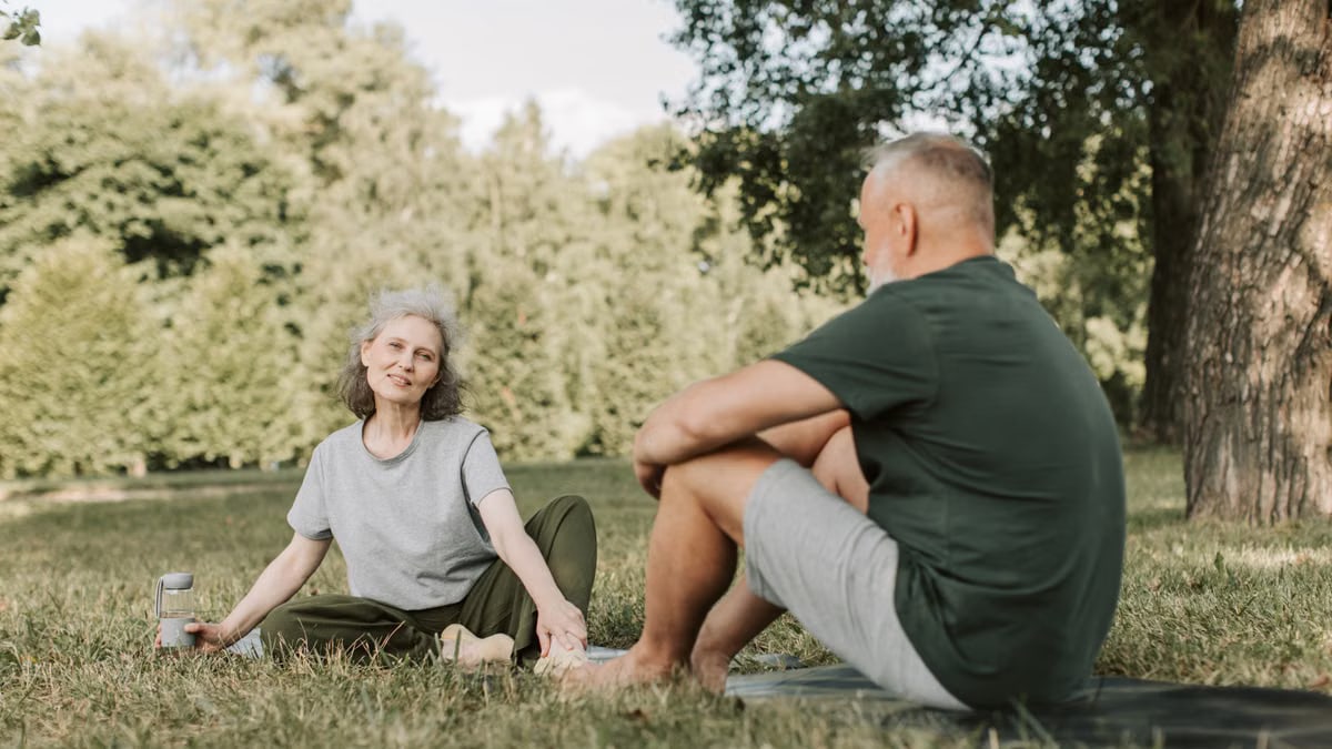 Senior couple practicing yoga and enjoying nature in a sunny park.